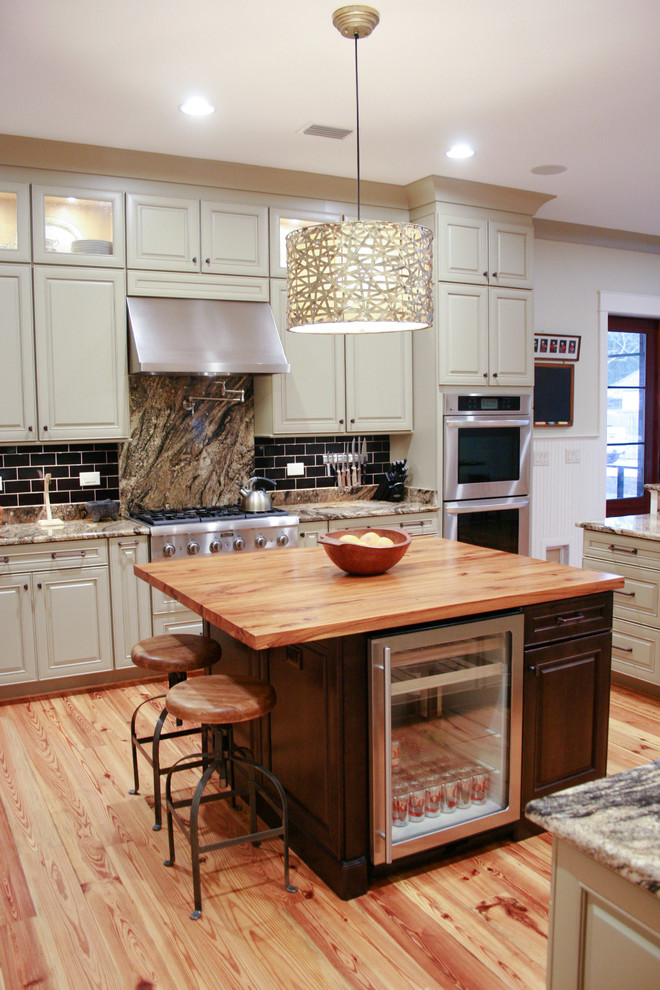 Modelo de cocina de estilo americano de tamaño medio con electrodomésticos de acero inoxidable, suelo de madera en tonos medios y una isla