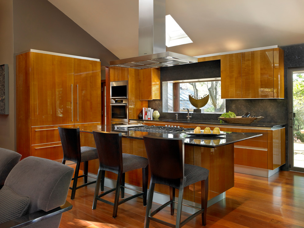 Imagen de cocina contemporánea abierta con armarios con paneles lisos, puertas de armario de madera oscura, salpicadero verde y electrodomésticos con paneles