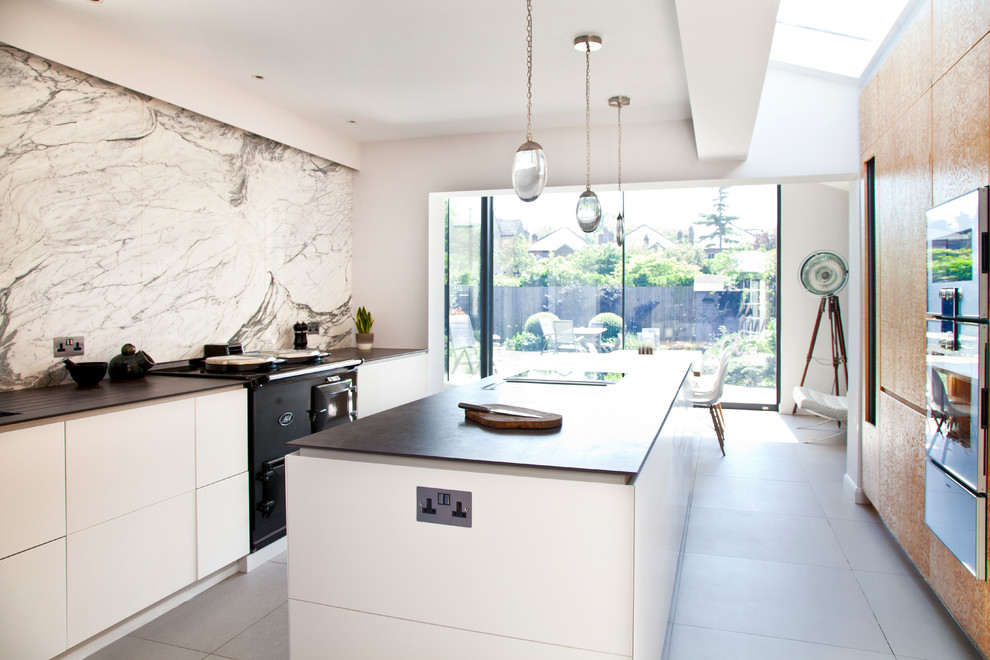 Inspiration for a large contemporary galley white floor eat-in kitchen remodel in London with a double-bowl sink, flat-panel cabinets, white backsplash, marble backsplash, stainless steel appliances, an island and black countertops