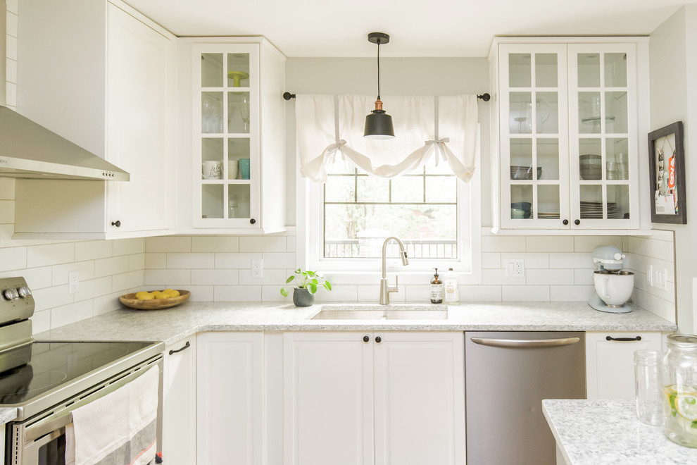 Klassisk inredning av ett mellanstort grå grått kök, med en undermonterad diskho, skåp i shakerstil, bänkskiva i kvartsit, vitt stänkskydd, stänkskydd i tunnelbanekakel, rostfria vitvaror, mellanmörkt trägolv, en köksö och brunt golv