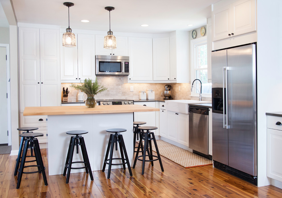 Example of a mid-sized trendy l-shaped medium tone wood floor eat-in kitchen design in Nashville with a farmhouse sink, recessed-panel cabinets, white cabinets, quartzite countertops, beige backsplash, stone tile backsplash, stainless steel appliances and an island