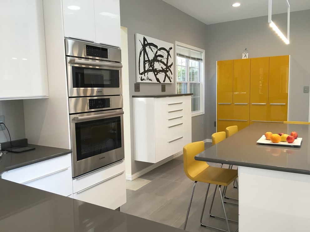 Design ideas for a medium sized modern u-shaped kitchen/diner in Austin with a submerged sink, flat-panel cabinets, white cabinets, black splashback, stone slab splashback, stainless steel appliances, an island and grey floors.