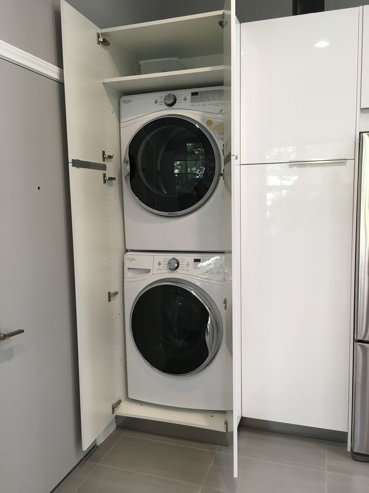 Immagine di una lavanderia moderna di medie dimensioni con lavello sottopiano, ante lisce, ante bianche, paraspruzzi nero, paraspruzzi in lastra di pietra e pavimento grigio