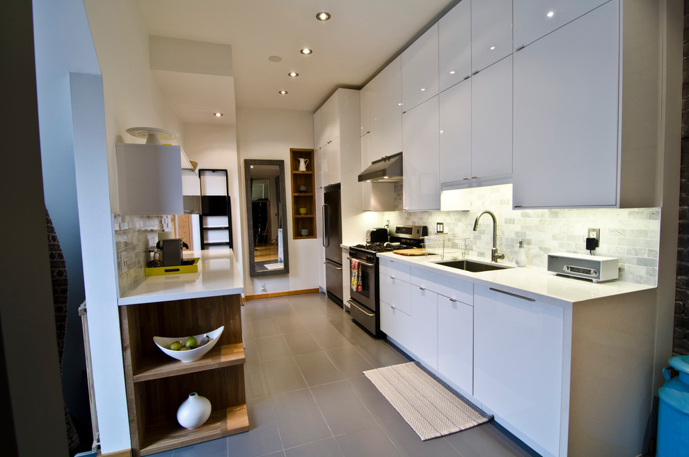 Einzeilige Moderne Küche mit flächenbündigen Schrankfronten, weißen Schränken, Küchenrückwand in Weiß, Rückwand aus Steinfliesen und schwarzen Elektrogeräten in Toronto