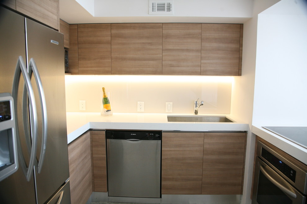 This is an example of a small modern u-shaped enclosed kitchen in Miami with a submerged sink, flat-panel cabinets, light wood cabinets, engineered stone countertops, beige splashback, glass sheet splashback, stainless steel appliances, marble flooring and an island.