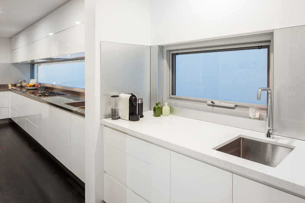 Moderne Küche mit Unterbauwaschbecken, flächenbündigen Schrankfronten, weißen Schränken, Quarzwerkstein-Arbeitsplatte, Küchenrückwand in Grau, Glasrückwand und weißer Arbeitsplatte in Perth
