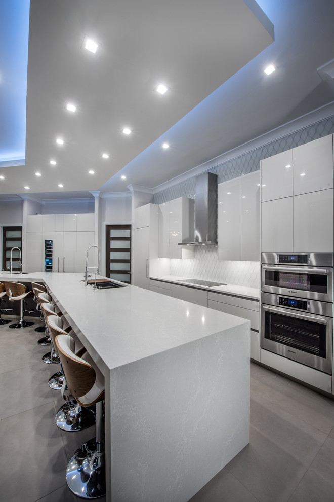 Large modern single-wall kitchen/diner in Miami with a submerged sink, flat-panel cabinets, white cabinets, quartz worktops, white splashback, ceramic splashback, stainless steel appliances, porcelain flooring, an island, grey floors and grey worktops.