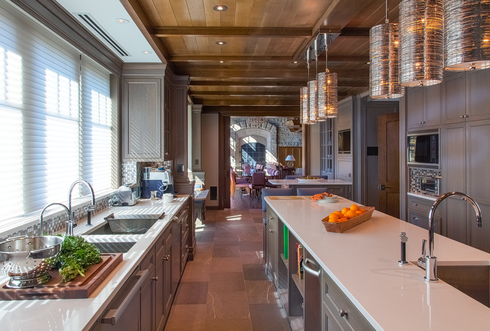 Huge arts and crafts u-shaped porcelain tile and brown floor eat-in kitchen photo in Burlington with recessed-panel cabinets, gray cabinets, stainless steel appliances, an island, a double-bowl sink, solid surface countertops, multicolored backsplash and mosaic tile backsplash