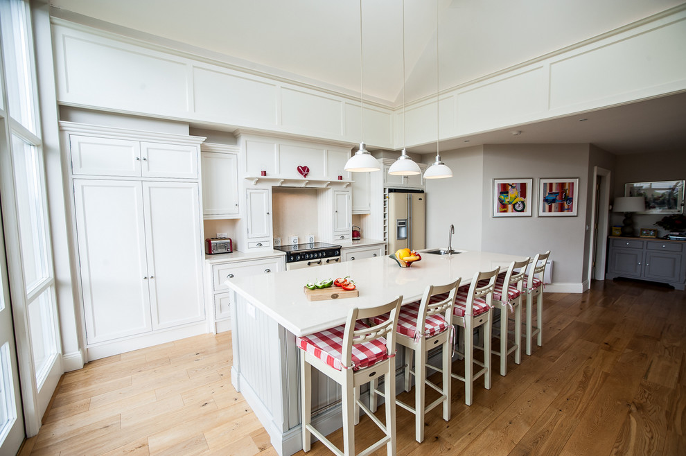 Bild på ett mellanstort vintage linjärt kök och matrum, med en dubbel diskho, luckor med infälld panel, bänkskiva i kvartsit, beige stänkskydd, stänkskydd i sten, färgglada vitvaror, mellanmörkt trägolv, en köksö och vita skåp