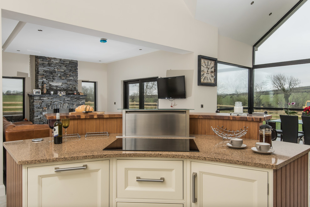 This is an example of a large contemporary l-shaped open plan kitchen in Belfast with a belfast sink, beaded cabinets, white cabinets, granite worktops, stainless steel appliances, porcelain flooring, an island, white floors and multicoloured worktops.