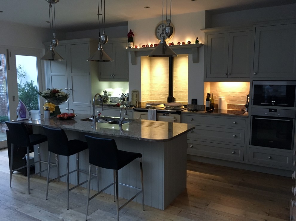Inspiration for a medium sized country galley open plan kitchen in Dublin with shaker cabinets, grey cabinets, granite worktops, metro tiled splashback, medium hardwood flooring and an island.