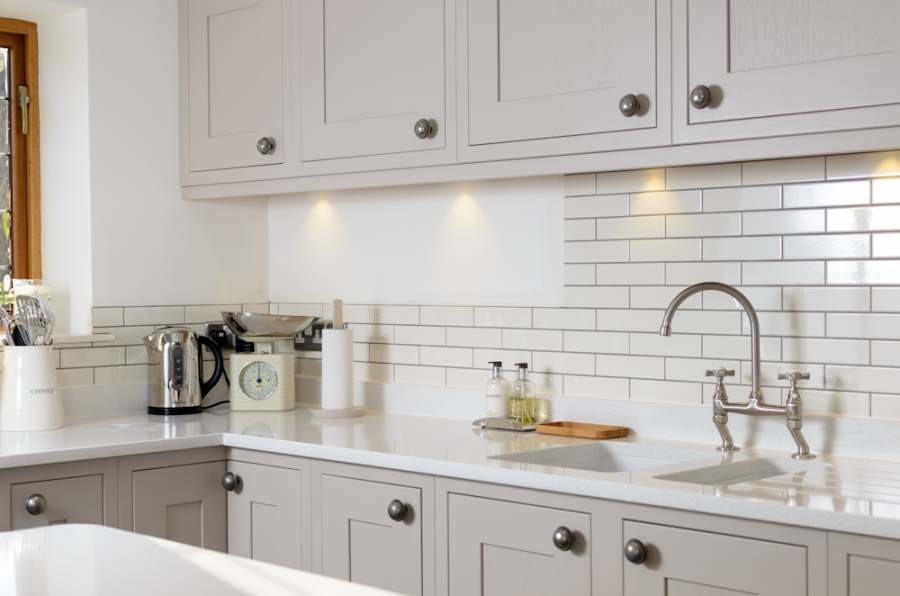 Stilmix Wohnküche mit Mineralwerkstoff-Arbeitsplatte, Rückwand aus Keramikfliesen, weißen Elektrogeräten und Kücheninsel in Sonstige