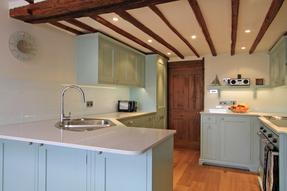 Transitional kitchen photo in Hampshire with a drop-in sink, blue cabinets, glass sheet backsplash and quartz countertops