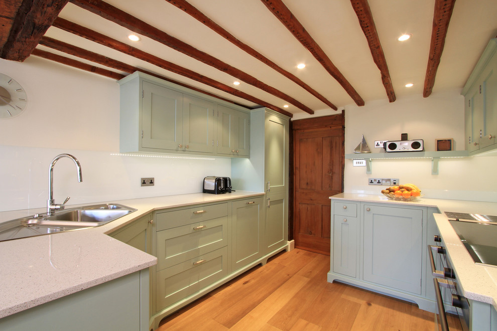 Klassische Küche mit Einbauwaschbecken, Schrankfronten im Shaker-Stil, grünen Schränken, Glasrückwand, Küchengeräten aus Edelstahl und Quarzwerkstein-Arbeitsplatte in Hampshire