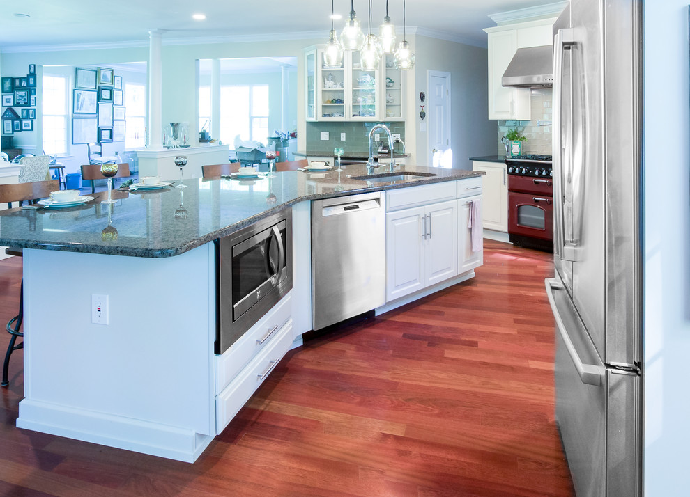 Bild på ett mycket stort vintage flerfärgad flerfärgat kök, med en undermonterad diskho, luckor med upphöjd panel, vita skåp, granitbänkskiva, grönt stänkskydd, stänkskydd i glaskakel, rostfria vitvaror, mellanmörkt trägolv och en köksö