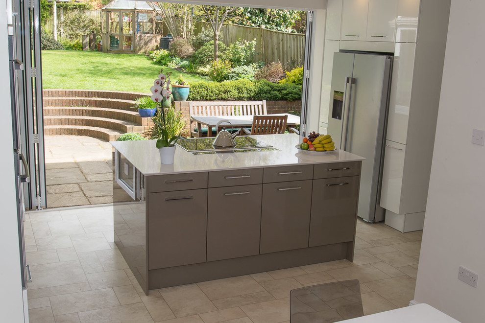 Inspiration for a medium sized contemporary kitchen/diner in Berkshire with flat-panel cabinets, white cabinets, glass sheet splashback, stainless steel appliances and an island.