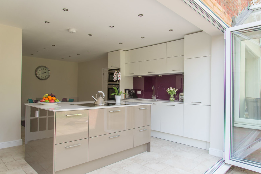 This is an example of a medium sized contemporary kitchen/diner in Berkshire with flat-panel cabinets, white cabinets, glass sheet splashback, stainless steel appliances and an island.