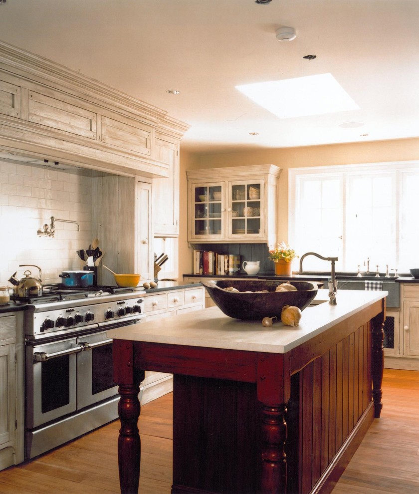 Ejemplo de cocina clásica con armarios estilo shaker, electrodomésticos de acero inoxidable, fregadero sobremueble, salpicadero blanco y salpicadero de azulejos tipo metro