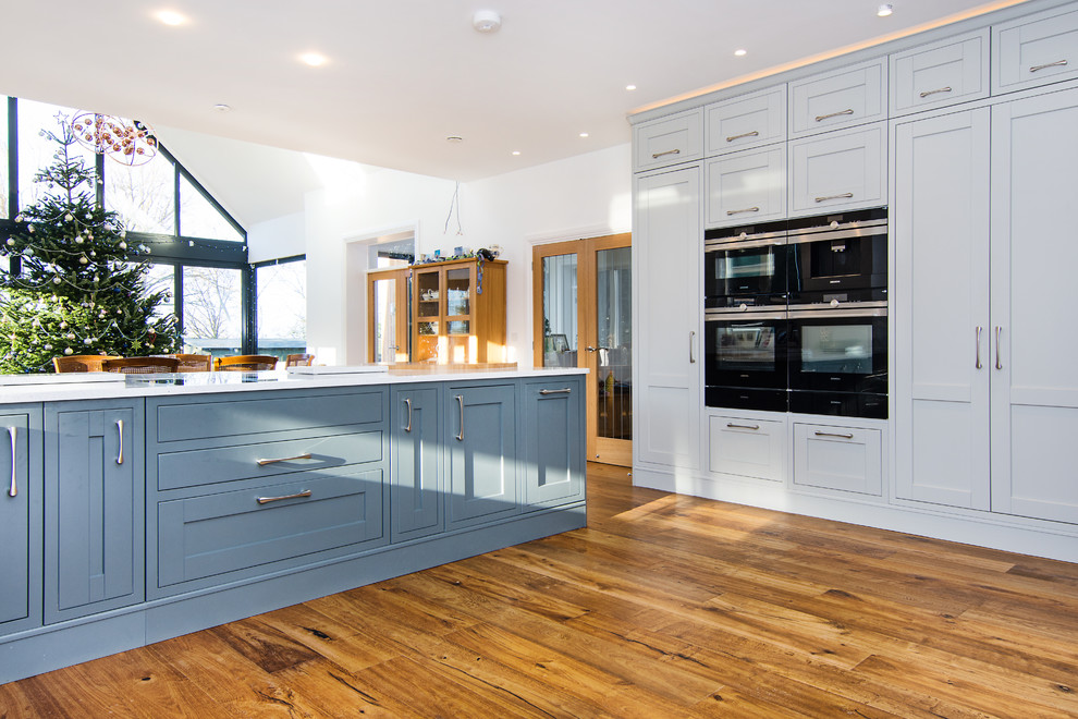 Esempio di una grande cucina classica con ante in stile shaker, ante blu, top in quarzite, elettrodomestici neri, parquet chiaro e top bianco