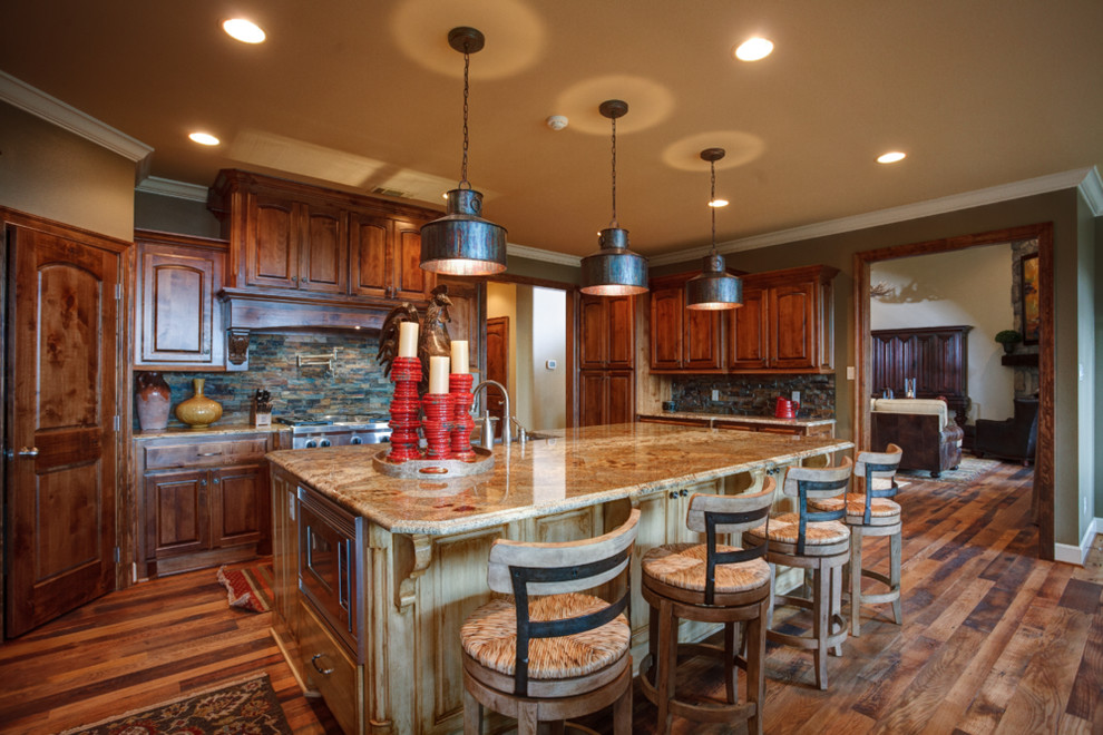 Mid-sized mountain style u-shaped dark wood floor and brown floor open concept kitchen photo in Little Rock with a farmhouse sink, raised-panel cabinets, dark wood cabinets, granite countertops, multicolored backsplash, stone tile backsplash, stainless steel appliances and an island