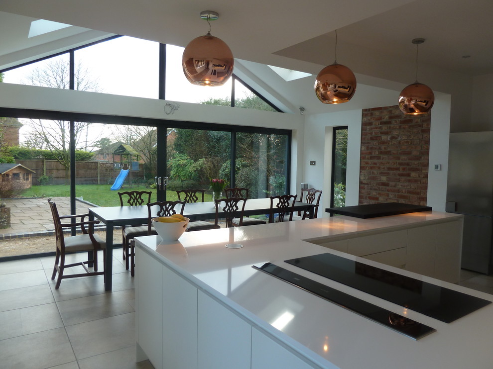 Medium sized contemporary u-shaped kitchen/diner in Berkshire with flat-panel cabinets, white cabinets, quartz worktops, grey splashback and a breakfast bar.