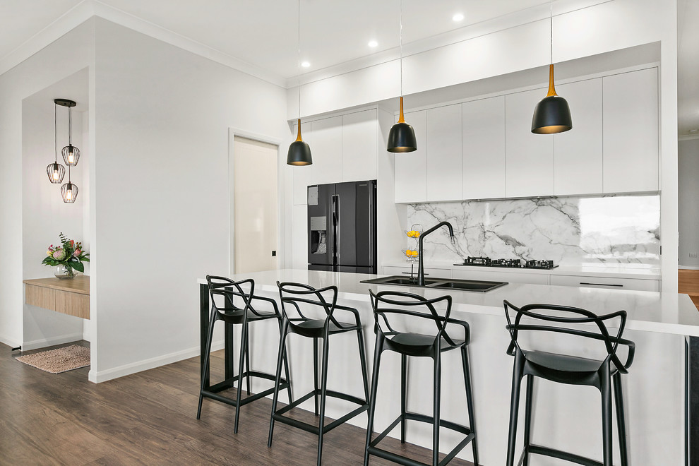 Idéer för ett modernt vit kök, med en dubbel diskho, släta luckor, vita skåp, vitt stänkskydd, stänkskydd i sten, en köksö och brunt golv