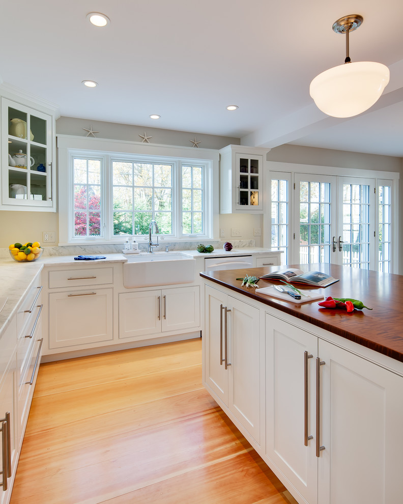 Klassisk inredning av ett mellanstort kök, med en rustik diskho, skåp i shakerstil, vita skåp, bänkskiva i kvartsit, ljust trägolv, en köksö och vita vitvaror