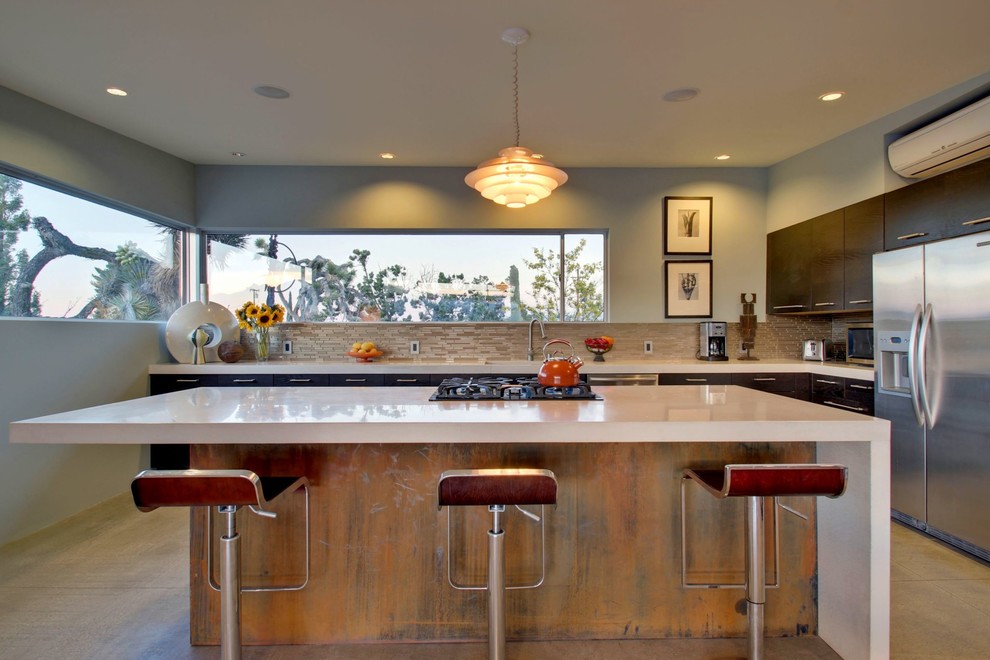 1950s u-shaped concrete floor eat-in kitchen photo in Los Angeles with flat-panel cabinets, dark wood cabinets, beige backsplash, stainless steel appliances and an island
