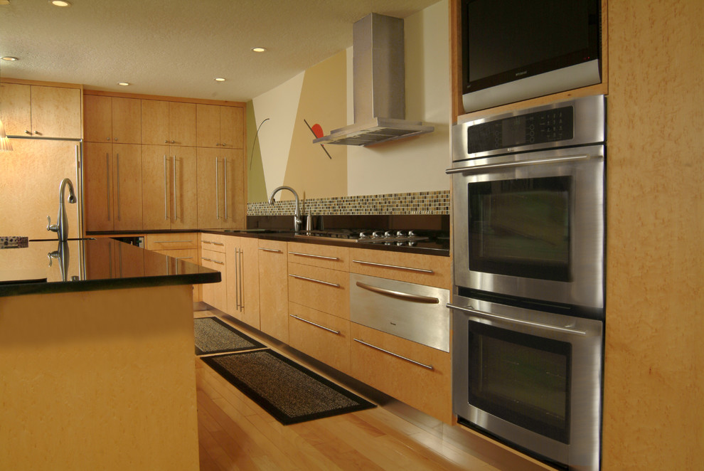 Exempel på ett modernt kök, med en undermonterad diskho, släta luckor, skåp i ljust trä, bänkskiva i onyx, stänkskydd med metallisk yta, stänkskydd i mosaik, rostfria vitvaror, ljust trägolv, en köksö och brunt golv