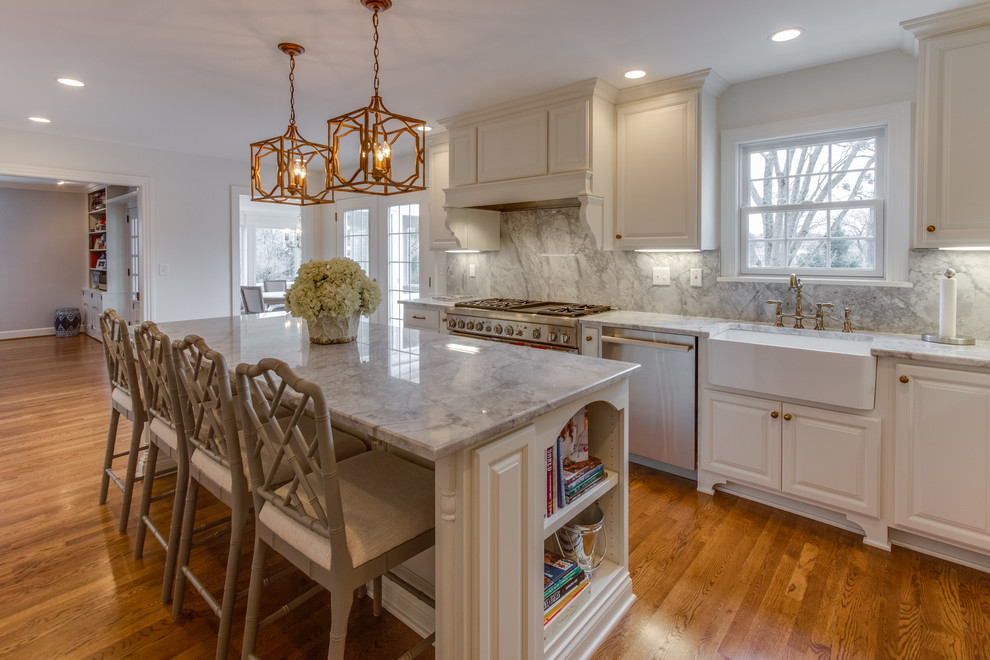 Inspiration for a mid-sized eclectic l-shaped medium tone wood floor eat-in kitchen remodel in Louisville with a farmhouse sink, raised-panel cabinets, white cabinets, quartzite countertops, white backsplash, stone slab backsplash, stainless steel appliances and an island