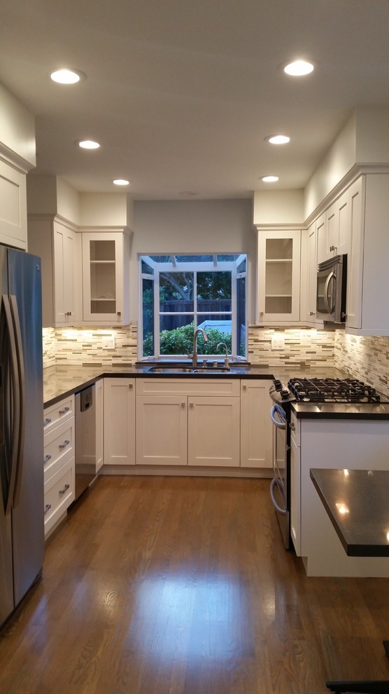 Inspiration for a mid-sized transitional u-shaped medium tone wood floor and brown floor eat-in kitchen remodel in Other with a double-bowl sink, shaker cabinets, white cabinets, quartz countertops, brown backsplash, matchstick tile backsplash, stainless steel appliances and no island