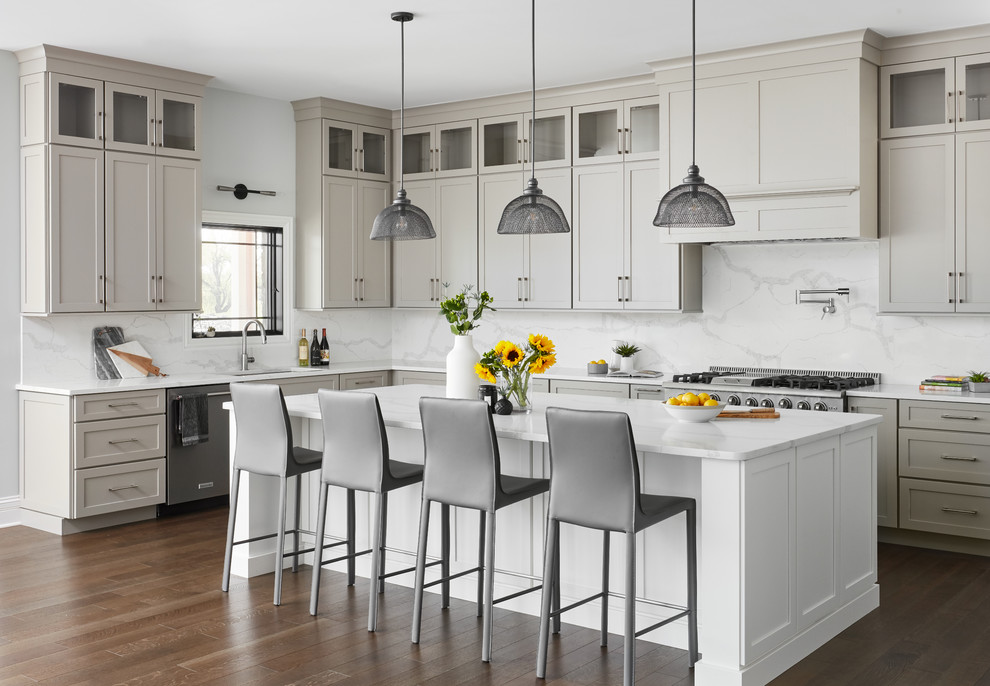 Expansive classic l-shaped kitchen in Chicago with engineered stone countertops, an island, a submerged sink, shaker cabinets, grey cabinets, white splashback, stone slab splashback, stainless steel appliances, dark hardwood flooring, brown floors and white worktops.