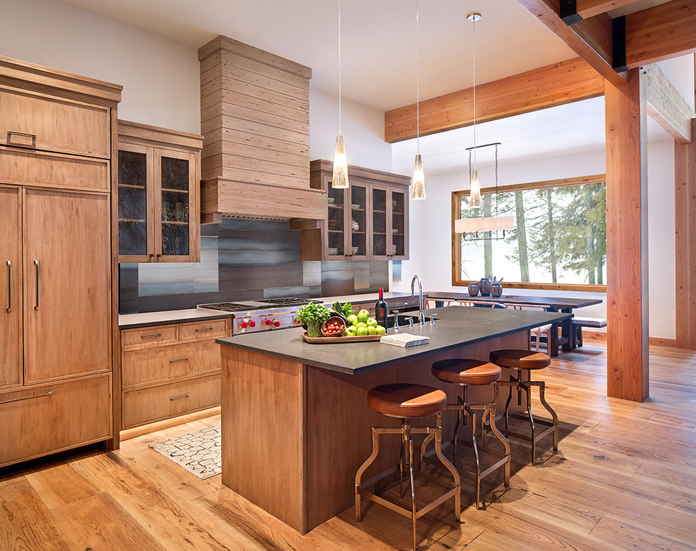 Rustikale Wohnküche mit Glasfronten, hellen Holzschränken, Küchengeräten aus Edelstahl, hellem Holzboden, Kücheninsel und beigem Boden in Sonstige