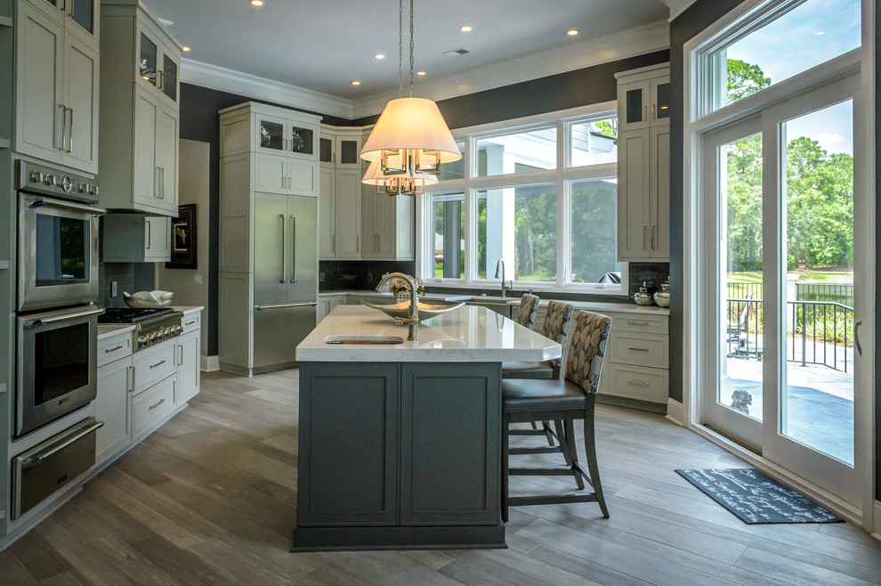 Mid-sized transitional u-shaped porcelain tile and brown floor eat-in kitchen photo in Charleston with a farmhouse sink, shaker cabinets, gray cabinets, glass tile backsplash, stainless steel appliances, an island, gray backsplash and quartz countertops