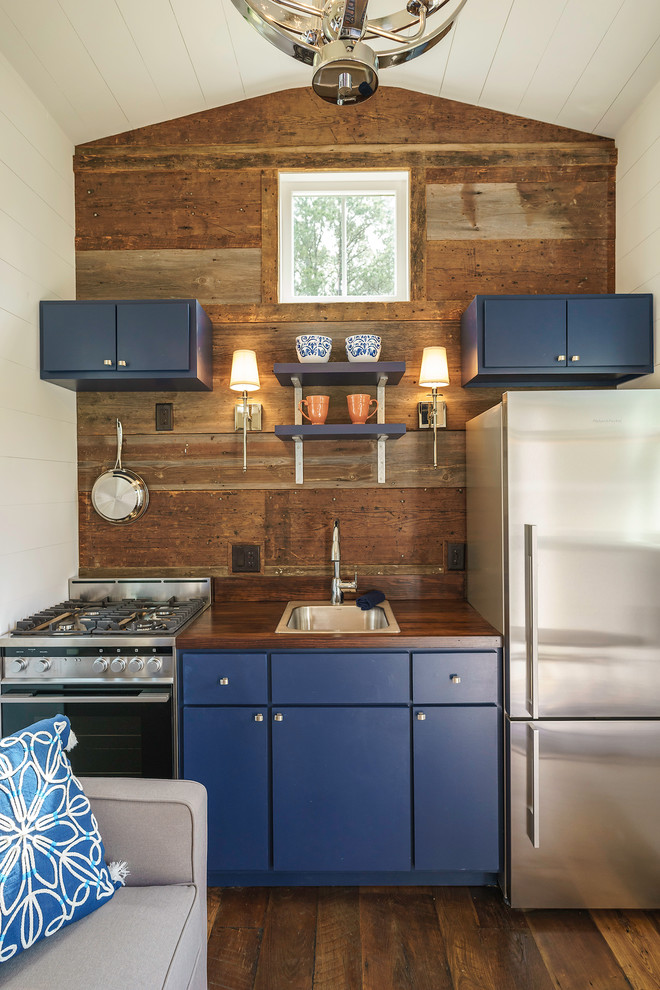 Foto di una piccola cucina lineare classica con lavello da incasso, ante lisce, ante blu, top in legno, elettrodomestici in acciaio inossidabile, parquet scuro e nessuna isola