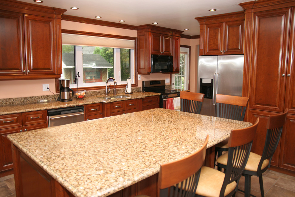 This is an example of a medium sized traditional l-shaped kitchen/diner in Los Angeles with a submerged sink, raised-panel cabinets, dark wood cabinets, granite worktops, stainless steel appliances, ceramic flooring, an island and brown floors.