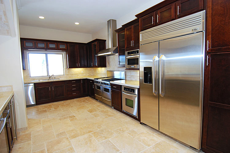 Photo of a large classic u-shaped kitchen/diner in Los Angeles with a submerged sink, shaker cabinets, dark wood cabinets, beige splashback, stainless steel appliances, travertine flooring, a breakfast bar, soapstone worktops, ceramic splashback, multi-coloured floors and beige worktops.