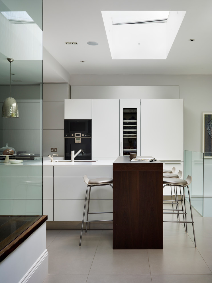 Imagen de cocina actual con armarios con paneles lisos, puertas de armario blancas y electrodomésticos negros