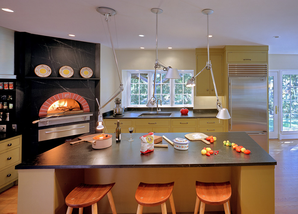 サンフランシスコにあるトランジショナルスタイルのおしゃれなキッチン (アンダーカウンターシンク、フラットパネル扉のキャビネット、黄色いキャビネット、黒いキッチンパネル、シルバーの調理設備) の写真