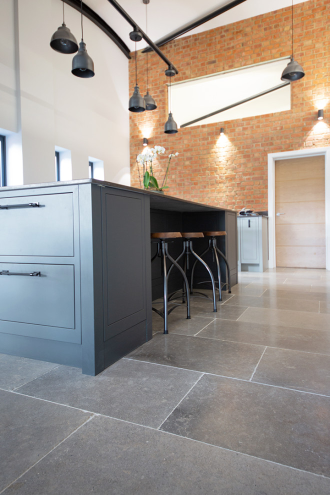 Esempio di una cucina industriale di medie dimensioni con pavimento in pietra calcarea, pavimento grigio e top nero
