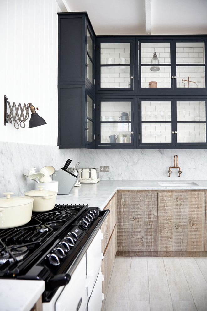 Inspiration for a scandinavian l-shaped light wood floor kitchen remodel in London with an undermount sink, glass-front cabinets, black cabinets, marble countertops, white backsplash, stone slab backsplash and white appliances