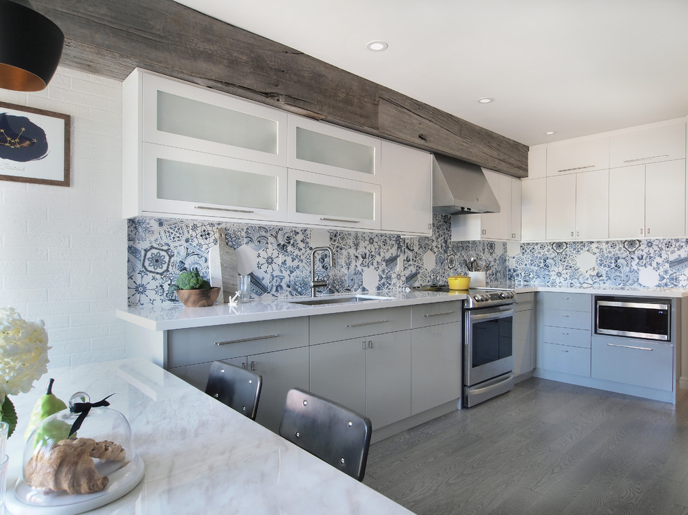 Exempel på ett mellanstort modernt kök, med en undermonterad diskho, släta luckor, vita skåp, bänkskiva i kvarts, blått stänkskydd, stänkskydd i porslinskakel, rostfria vitvaror, mellanmörkt trägolv och grått golv