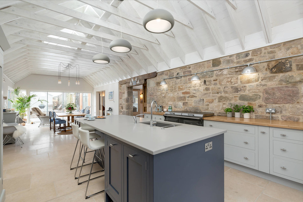 Inspiration for a large farmhouse travertine floor eat-in kitchen remodel in Edinburgh with flat-panel cabinets, gray cabinets, quartzite countertops, stainless steel appliances, an island and an undermount sink