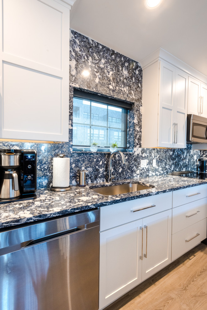 This is an example of a medium sized industrial l-shaped kitchen/diner in Baltimore with a submerged sink, white cabinets, engineered stone countertops, blue splashback, engineered quartz splashback, stainless steel appliances, vinyl flooring, brown floors and blue worktops.