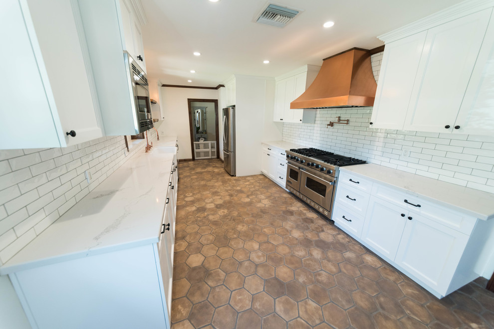Photo of a medium sized urban u-shaped kitchen/diner in San Francisco with flat-panel cabinets, white cabinets, a belfast sink, quartz worktops, ceramic splashback, stainless steel appliances, terracotta flooring and brown floors.