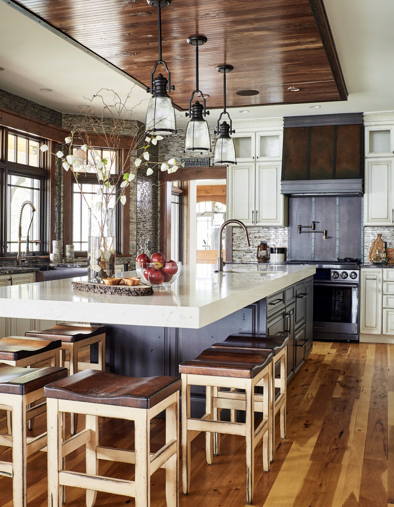 Ejemplo de cocina rústica grande con fregadero sobremueble, armarios con paneles empotrados, puertas de armario blancas, encimera de cuarzo compacto, salpicadero verde, suelo de madera en tonos medios, una isla, suelo marrón, encimeras blancas, salpicadero con mosaicos de azulejos y electrodomésticos de acero inoxidable