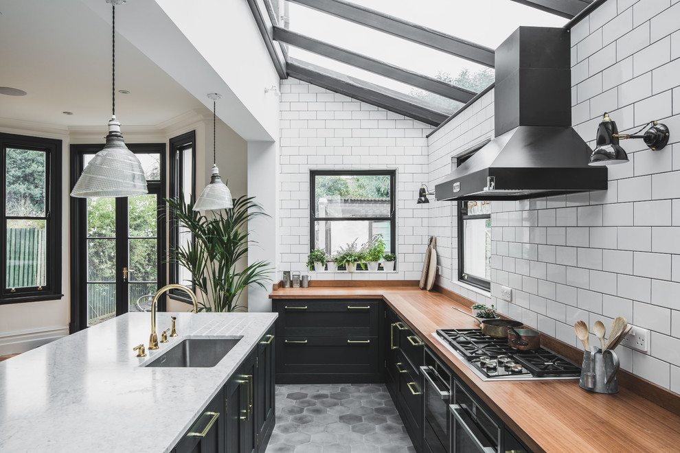 Diseño de cocina comedor industrial grande con fregadero bajoencimera, armarios estilo shaker, encimera de madera, salpicadero blanco, salpicadero de azulejos tipo metro, una isla, suelo gris, suelo de azulejos de cemento y con blanco y negro