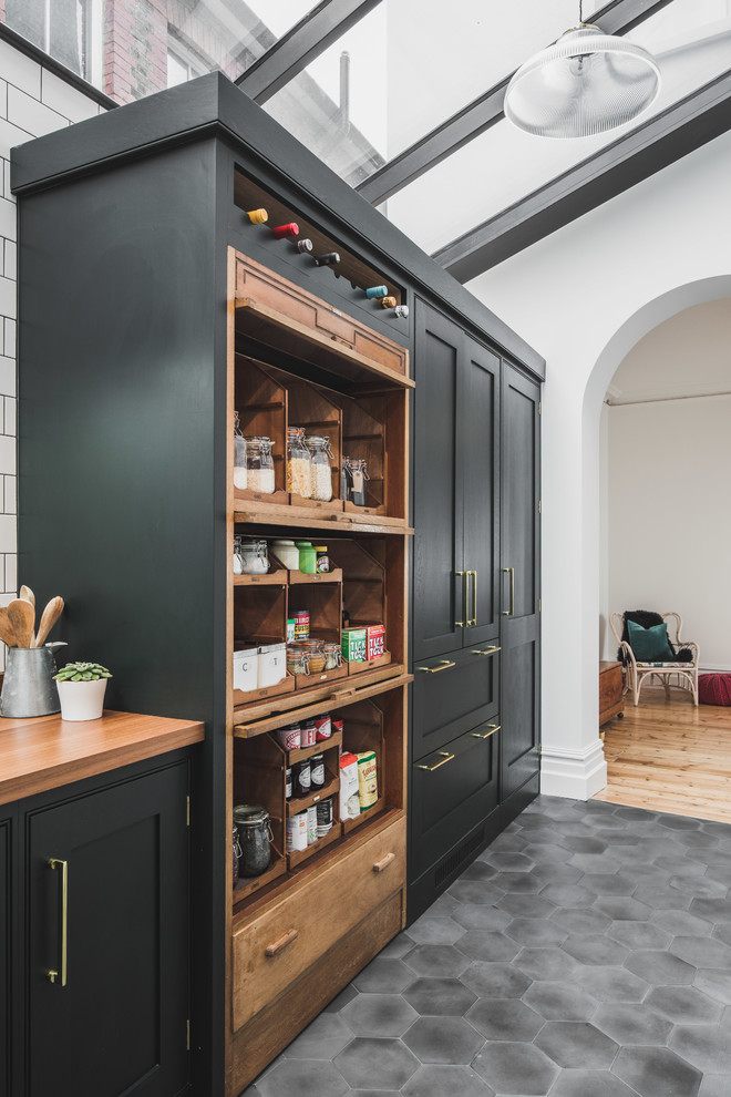 Large industrial l-shaped kitchen/diner in London with a submerged sink, shaker cabinets, green cabinets, marble worktops, white splashback, metro tiled splashback, stainless steel appliances, cement flooring, an island and grey floors.