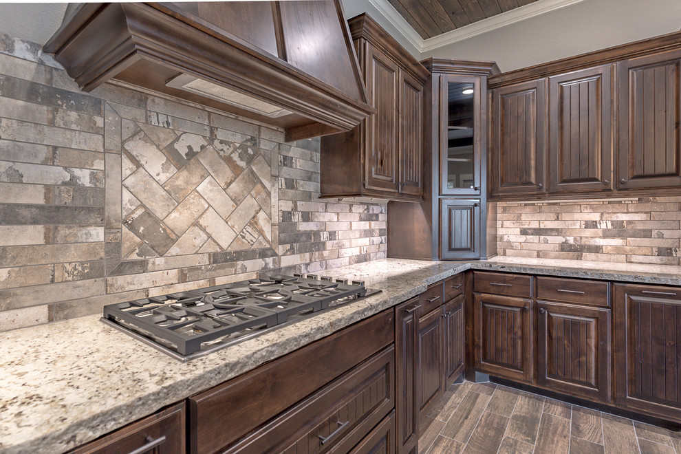 Mid-sized urban u-shaped ceramic tile and brown floor kitchen pantry photo in Other with a farmhouse sink, raised-panel cabinets, dark wood cabinets, granite countertops, multicolored backsplash, brick backsplash, stainless steel appliances and an island
