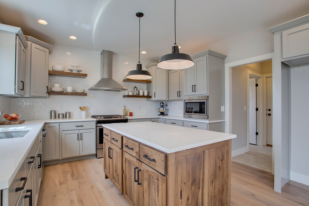 Mid-sized country u-shaped light wood floor and beige floor eat-in kitchen photo in Chicago with an undermount sink, shaker cabinets, gray cabinets, quartz countertops, white backsplash, subway tile backsplash, stainless steel appliances, an island and white countertops